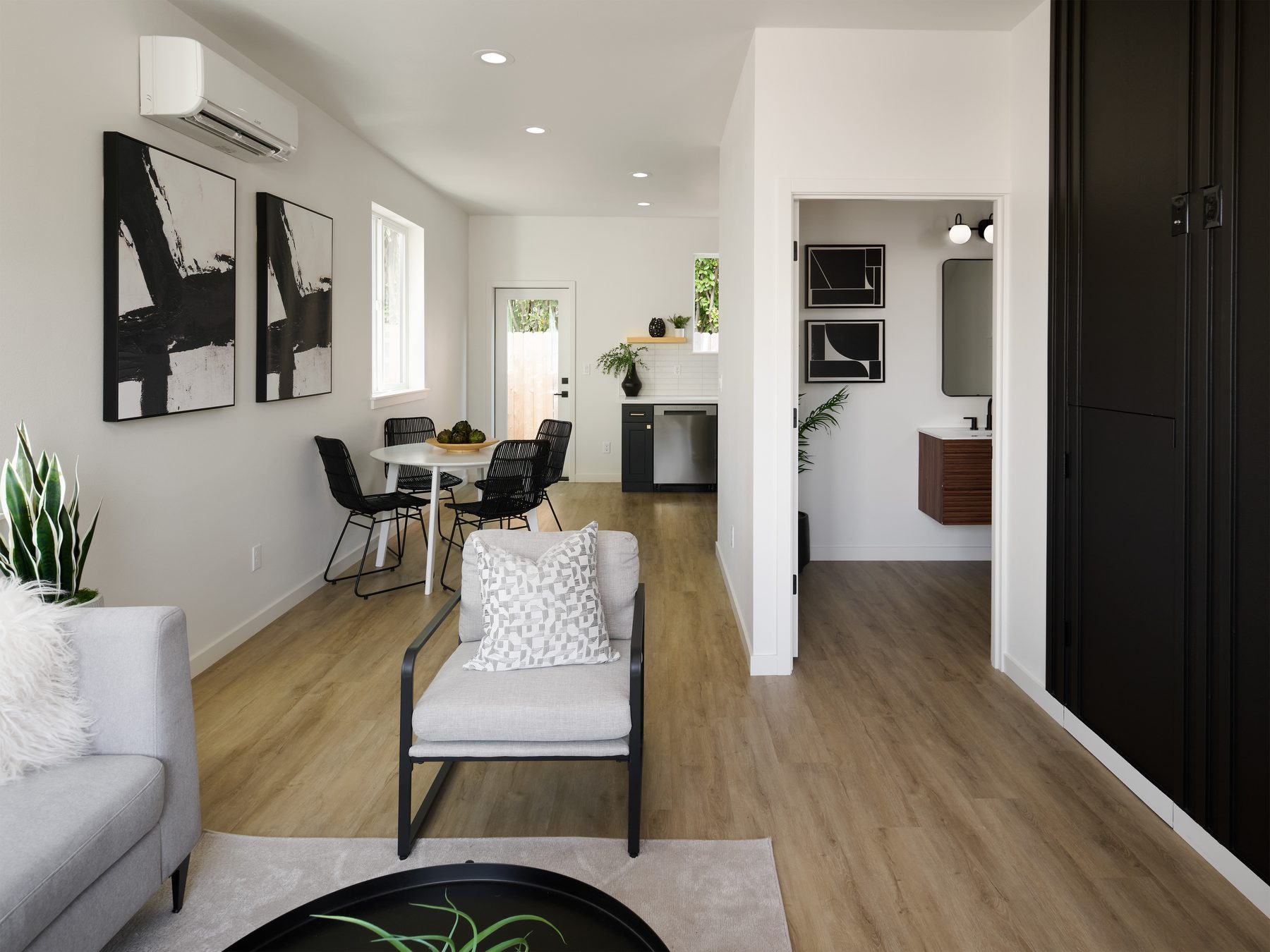 Open living and dining space with mini-split, black cabinetry, and wide-plank floors