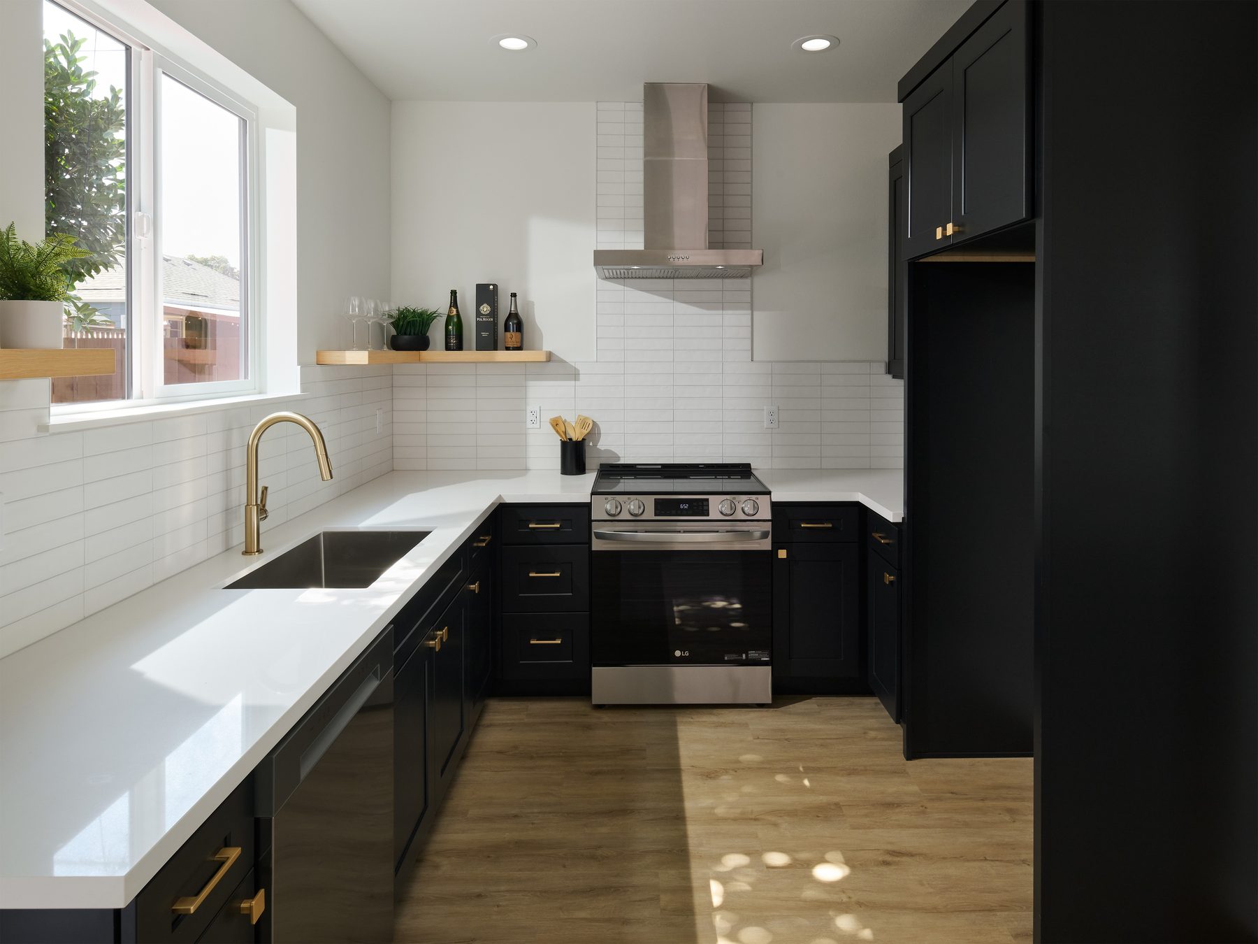 Black shaker kitchen with brass hardware, white quartz counters, and subway tile