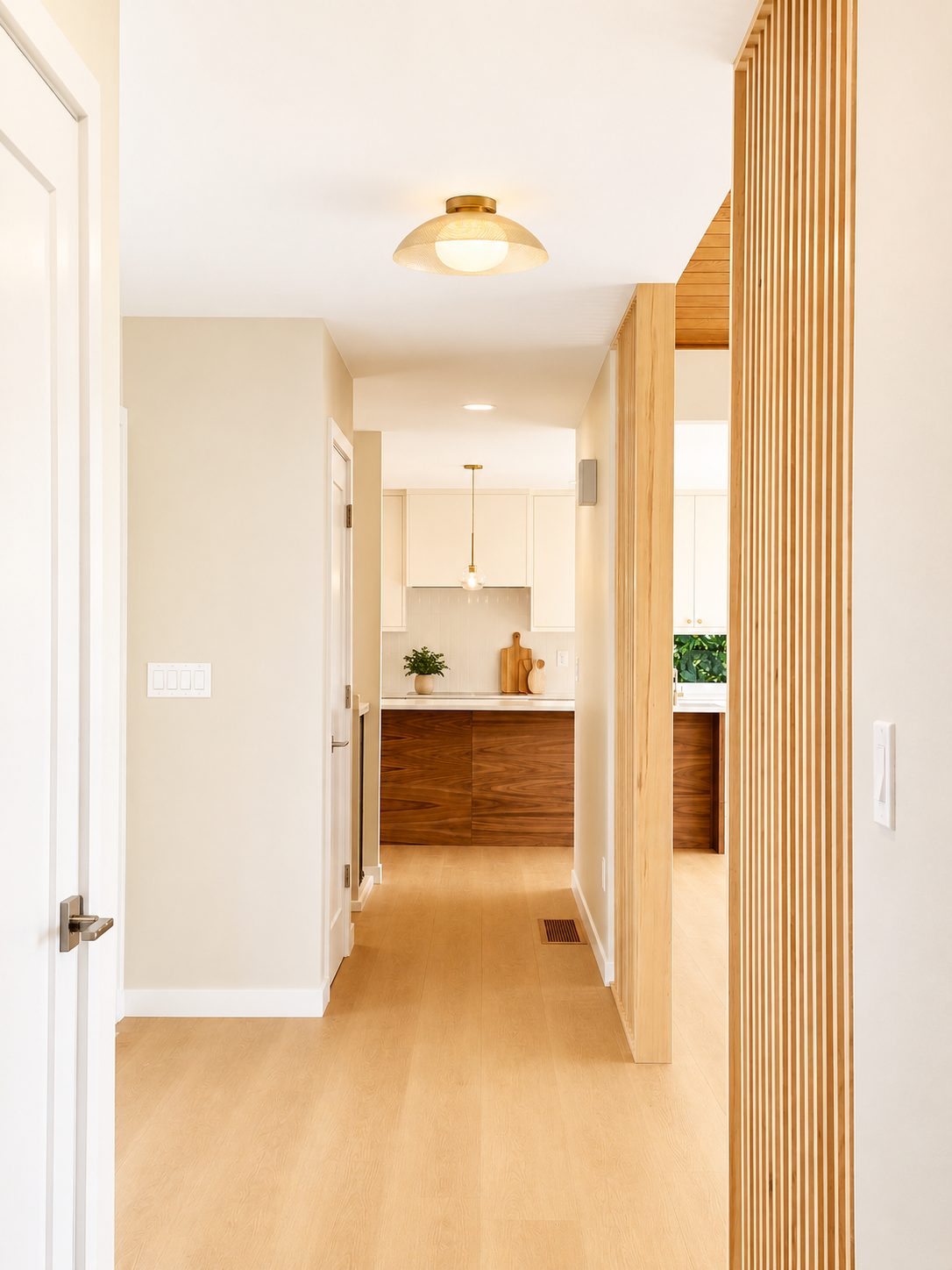 Entry hall with wood-slat screen opening to the walnut kitchen